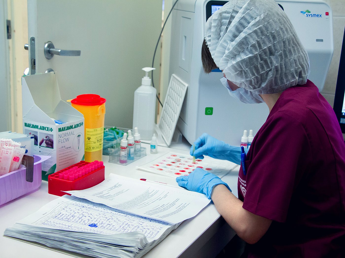 Profesional de laboratorio procesando muestras clínicas sobre una mesa de trabajo.
